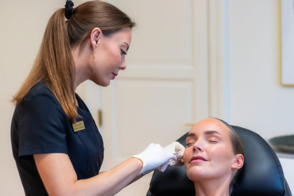 Kosmetisk sygeplejerske Desiree Hove giver filler ved kinden, patienten ligger i behandlingsstolen