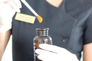 Behandler dypper en pensel i kemisk peel fra en brun glasflaske
